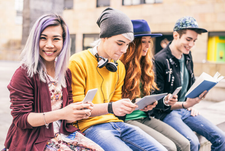 Vier jongeren kijkend op een tablet of telefoon.